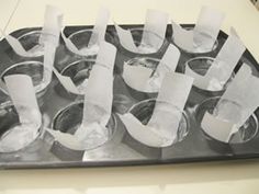 several cups are lined up on a tray with tissue paper in them and the letters cut out