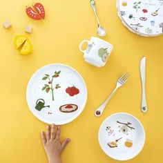 someone is holding their plate over the table with other plates and utensils on it