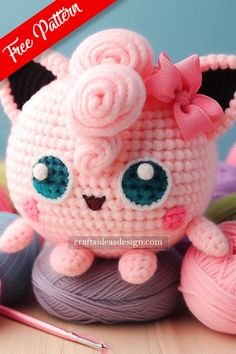 a crocheted pink cat sitting on top of a ball of yarn