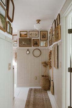 a hallway with pictures on the wall and a rug