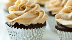 several cupcakes with frosting on them sitting on a white tableclothed surface