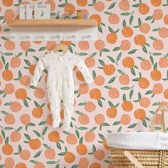 a baby's clothes hanging on a wall next to a basket with an orange print