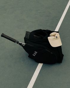 a tennis racket laying on the ground next to a black bag and white stripe