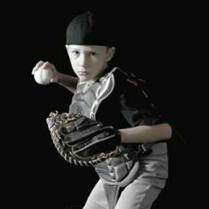 a young boy is holding a baseball and glove