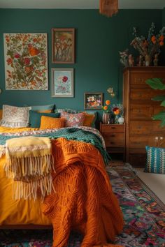 a bedroom with green walls and orange blankets on the bedspread is decorated with flowers