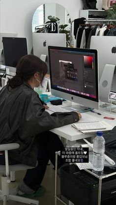 a woman sitting at a desk with a computer on her lap and wearing a face mask