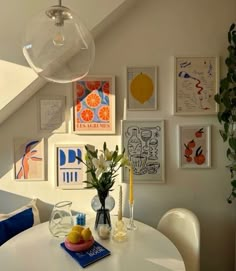 a white table and chairs in a room with pictures on the wall