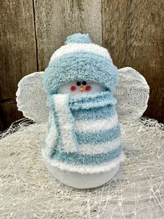 a small stuffed animal wearing a blue and white striped scarf on top of a pile of hay