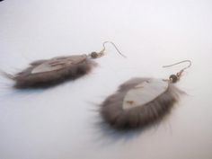 two feather earrings are shown on a white surface