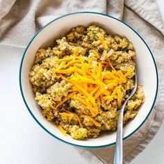 a bowl filled with oatmeal and cheese on top of a cloth next to a spoon