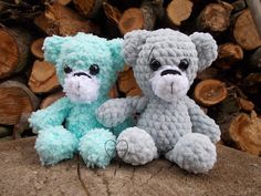 two crocheted teddy bears sitting next to each other on top of a log