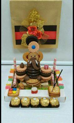 an elephant statue sitting on top of a table filled with cakes and pastries in front of a painting