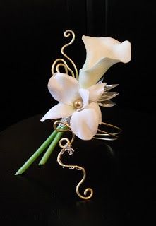 a white flower on a black table with gold spirals and pearls in the center