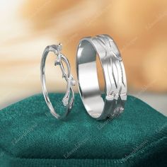 two wedding rings sitting next to each other on top of a green cloth in front of a