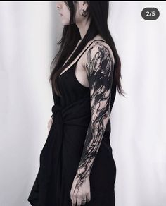 a woman with long black hair and tattoos on her arm is standing in front of a white wall