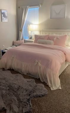 a bedroom with a large bed and pink comforter on the floor next to a window