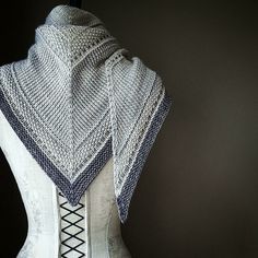 a white mannequin wearing a knitted shawl