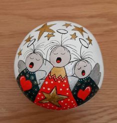 a painted rock with three little angels on it's face and stars around the top