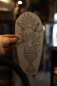 a person holding up a paper cutout with an image of a vase on it