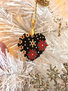 an ornament hanging from a christmas tree in the shape of a heart with red and green beads