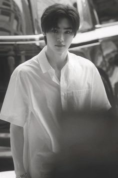 black and white photograph of a young man standing in front of a car