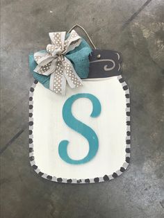 a door hanger with a monogrammed s on it and a ribbon tied around the letter