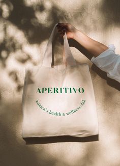 a woman's hand holding a shopping bag with the words aperitvo on it