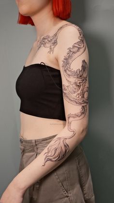 a woman with red hair and dragon tattoos on her arm is posing for the camera