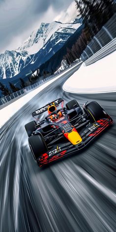 a red and yellow race car driving on a snowy road with mountains in the background