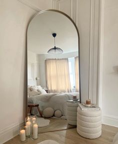 a mirror sitting on top of a wooden floor next to a white couch and candles