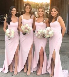 bridesmaids in pink dresses posing for the camera with their bridal bouquets