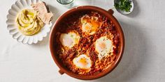 three eggs are in a pan with sauce and tortilla chips on the side