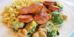 a white plate topped with pasta and sausage next to broccoli covered in sauce