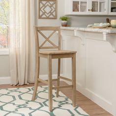 a wooden bar stool sitting on top of a rug in front of a kitchen counter