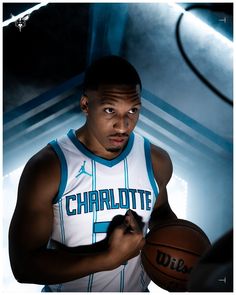 a man holding a basketball in his right hand and looking at the camera with an intense look on his face