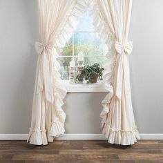 a window with ruffled curtains and a potted plant