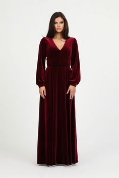 a woman wearing a long red velvet dress with deep v - neckline and sleeves