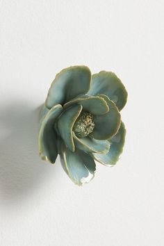 a large green flower sitting on top of a white wall