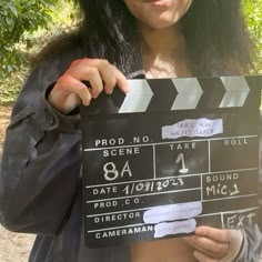 a woman holding up a clapper board in front of her face