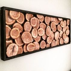 a group of cut up logs mounted on a wall next to a white wall with a black frame