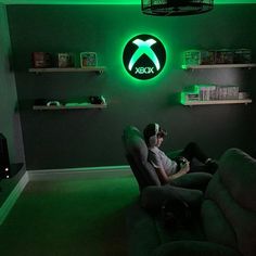 a man sitting in a reclining chair under a neon green logo on the wall