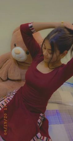 a woman sitting on top of a bed next to a teddy bear