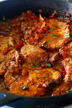 a pan filled with meat covered in sauce and garnished with parsley on the side