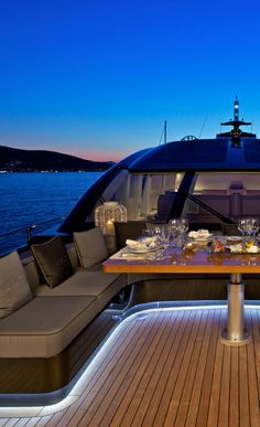 a dining table on the deck of a boat at night with lit candles and wine glasses