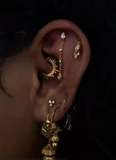 a close up of a person wearing gold ear rings and piercings on their ears