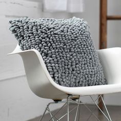 a gray and white pillow sitting on top of a chair