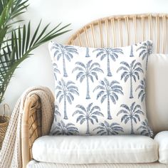 a white couch with a blue palm tree pillow on it next to a wicker basket