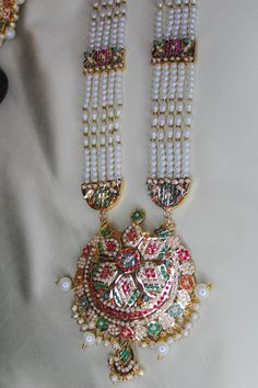 Discover the perfect piece of jewelry for your next special occasion with this exquisite gold-plated jadau ranihaar set. Add some sparkle to your look! NOTE: - It takes 11-25 working days minimum For Delivery. and sometimes it takes 3-4 weeks for delivery due to customs clearance and depending upon the location. We would always love to serve you. Thank you for shopping with us. White 22k Gold Kundan Necklace For Diwali, Diwali White Kundan Necklace In 22k Gold, Eid Jewelry With Zari Work For Puja, 22k Gold Meenakari White Jewelry, Zari Work Jewelry For Eid Puja, Zari Work Jewelry For Puja And Eid, Gold Plated Meenakari Jewelry For Puja, Gold Pearl Necklace With Meenakari For Festive Occasions, Kundan Pearl Necklace With Meenakari For Puja