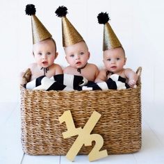 three babies wearing party hats sitting in a basket with the number twenty seven on it