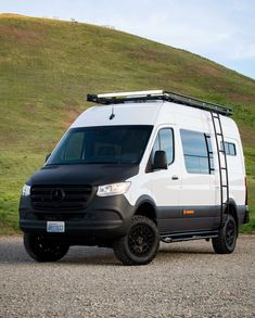 a white van parked on the side of a road next to a green hill and grass covered hillside